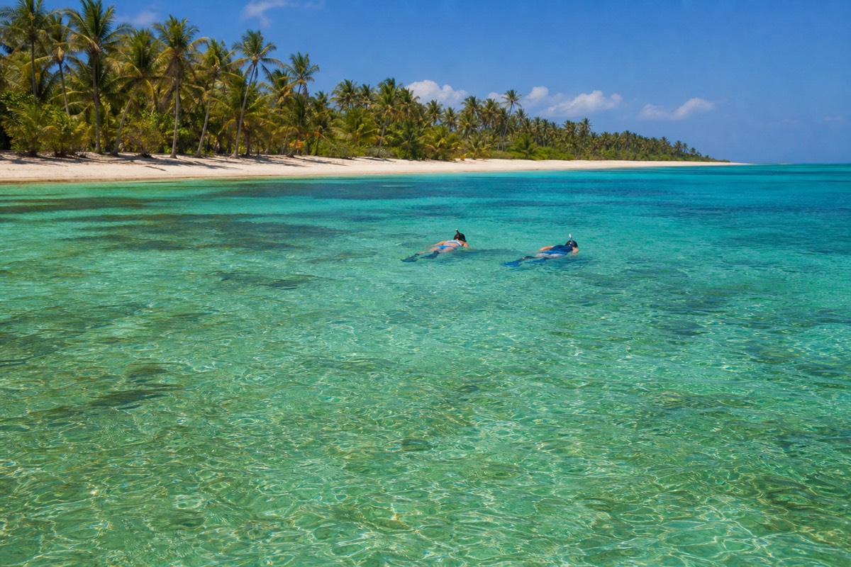 A family snorkelling together in shallow clear water over a reef flat on Roatán